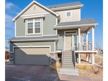 Inviting two-story home with a covered porch, attached garage, and manicured landscaping at 16347 E 111Th Dr, Commerce City, CO 80022