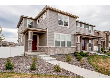 Charming two-story home with neutral siding, brick accents, a walkway and manicured landscaping at 5152 Bittercress Rd, Brighton, CO 80640