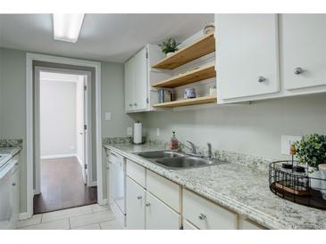 Bright kitchen featuring granite countertops, white cabinets, and floating wood shelves at 9995 E Harvard Ave # 155, Denver, CO 80231