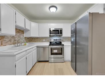 Modern kitchen features stainless steel appliances, white cabinets, and neutral backsplash at 635 S Alton Way # 6A, Denver, CO 80247