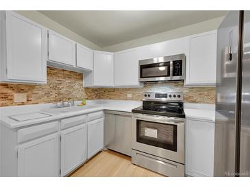 Bright kitchen features white cabinets, stainless steel appliances, and stylish backsplash at 635 S Alton Way # 6A, Denver, CO 80247
