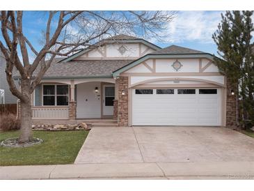 Charming home featuring a two-car garage, stone accents, and a welcoming covered porch at 9450 Troon Village Dr, Lone Tree, CO 80124