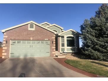 Charming brick home featuring an attached two-car garage, well-kept lawn, and shade tree at 1998 E 100Th Pl, Thornton, CO 80229