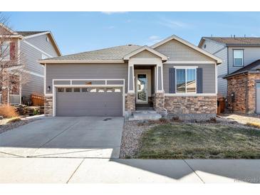 Charming single-Gathering home featuring stone accents, a gray exterior, and an attached two-car garage at 7426 Blue Water Ln, Castle Rock, CO 80108