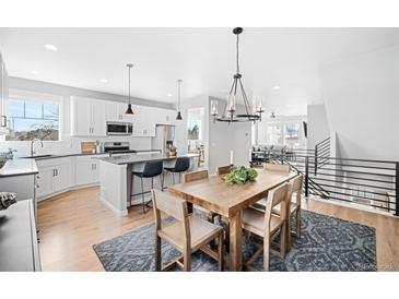 Open concept kitchen with island, white cabinets, and hardwood floors at 5245 W 97Th Ave, Broomfield, CO 80020