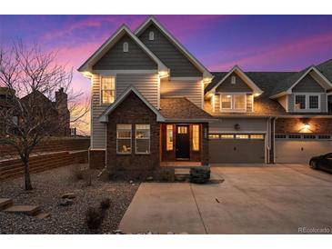 Charming two-story home with brick and gray siding and an attached two-car garage, captured during a vibrant sunset at 6854 Carr St, Arvada, CO 80004