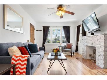 Bright living room with a gray sofa, a stone fireplace, and many windows at 3319 E 27Th Ave, Denver, CO 80205