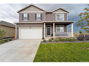 Two-story house with gray siding, white garage door, and landscaped front yard at 1123 Sunrise Dr, Brighton, CO 80603