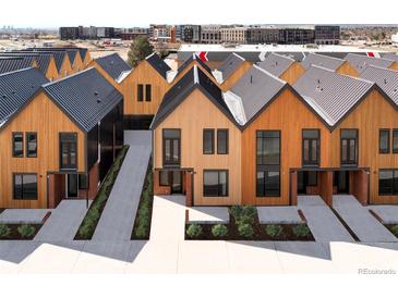 Modern townhomes showing a landscaped walkway to the front door and featuring contemporary wood and dark metal siding at 9171 Eaton St, Westminster, CO 80031