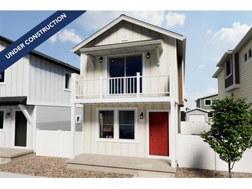 Charming two-story home showcasing a balcony, red front door, white picket fence and modern architectural details at 10379 Vaughn Way, Commerce City, CO 80022