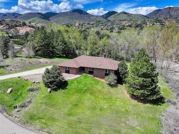 Stunning single-story brick home with beautiful mountain views and a lush green lawn at 6155 Meadowbrook Dr, Morrison, CO 80465