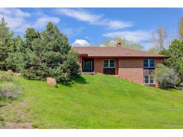 Charming brick home featuring a well-manicured lawn and mature tree providing shade and curb appeal at 6155 Meadowbrook Dr, Morrison, CO 80465