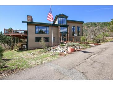 Inviting two-story home with a deck and lush landscaping. Front yard has american flag and stone features at 6584 Pike Cir, Larkspur, CO 80118