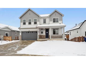 Two-story house with gray and white siding, a two-car garage, and a snowy front yard at 692 Apex Rise St, Erie, CO 80516