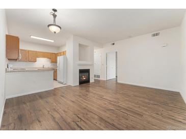 Open-concept living room features a cozy fireplace and adjacent kitchen with stainless appliances at 3205 S Walden Ct # B, Aurora, CO 80013
