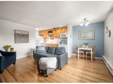 Bright living room featuring hardwood floors, a comfortable gray sofa and an adjacent dining space at 155 S Pennsylvania St # 310, Denver, CO 80209