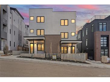 Contemporary townhome with a modern facade, clean lines, and a landscaped front yard under a colorful dusk sky at 1252 Yates St, Denver, CO 80204