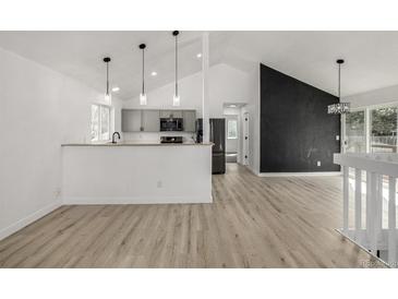 Open-concept living space with hardwood floors, gray cabinets, and modern pendant lighting at 17486 E Plateau Dr, Aurora, CO 80015