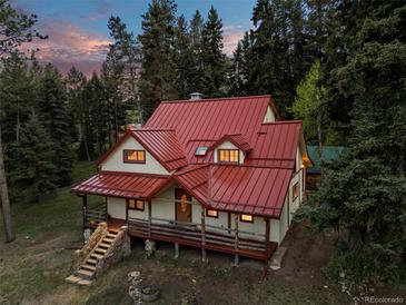 Charming home featuring a red metal roof, covered porch, and a stone stairway at 8821 Blue Creek Rd, Evergreen, CO 80439