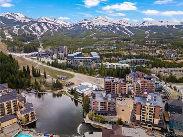 Stunning aerial view of a mountain town with ski slopes, lodging, and a tranquil lake in the foreground at 405 Village Rd # 101, Breckenridge, CO 80424