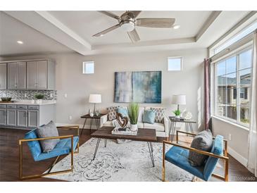 Bright living room with modern decor, plush seating, and a decorative ceiling fan at 8095 E 128Th Pl, Thornton, CO 80602