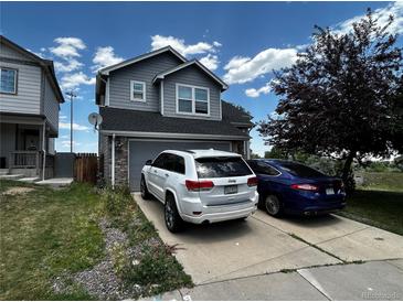 A two-story home with gray siding, a two car garage, and a concrete driveway on a sunny day at 2005 W 86Th Ave, Denver, CO 80260