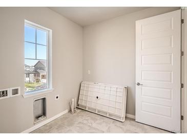 Bright laundry room features a large window, modern tile flooring, and utility connections at 2560 Wesley Ln, Lafayette, CO 80026