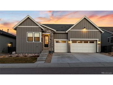 Beautiful exterior elevation showcasing a two-car garage, gray siding, stone accents, and manicured front yard at 11412 Autumn Moon St, Littleton, CO 80125
