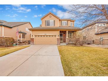 Charming two-story home featuring a well-maintained lawn and a spacious driveway leading to the garage at 15112 E 116Th Pl, Commerce City, CO 80603