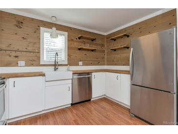 Bright kitchen with stainless steel refrigerator, a farmhouse sink, butcher block countertop, and natural wood plank walls at 5700 W 28Th Ave # 6, Wheat Ridge, CO 80214