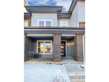 Two-story townhome with gray siding, brick accents, and a covered porch at 14948 E Belleview Ave, Aurora, CO 80015
