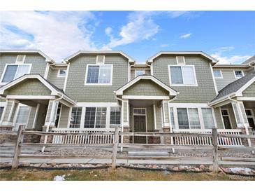 Charming townhome featuring a well-kept, green exterior with stone accents and a cozy front porch at 15945 E Geddes Dr # 54, Aurora, CO 80016