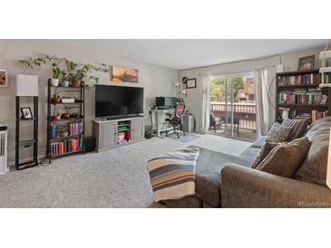 Inviting living room with balcony access, cozy gray couch, and a dedicated workspace at 7755 E Quincy Ave # 207A3, Denver, CO 80237