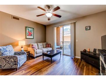 Bright living room featuring wood floors, ceiling fan, and access to a private outdoor balcony at 1651 W Canal Cir # 613, Littleton, CO 80120