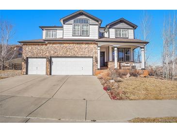 Charming two-story home featuring a stone facade, three car garage, and welcoming front porch at 8726 Gardenia Cir, Arvada, CO 80005