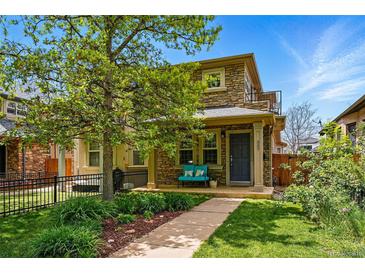 Charming stone-clad two-story home with landscaped front yard and inviting blue bench on the front porch at 557 S Clarkson St, Denver, CO 80209