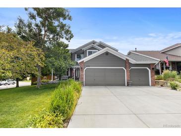 Charming two-story home features a three-car garage, lush lawn, mature tree, and meticulously maintained landscaping at 6772 Tiger Tooth, Littleton, CO 80124