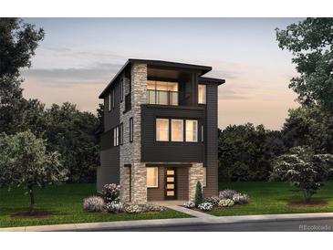Modern three-story home featuring stone accents, a balcony, and a well-manicured lawn at 8628 Hotchkiss St, Littleton, CO 80125