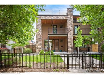 Contemporary multi-story home with stone accents, a balcony, manicured lawn and a black metal fence at 2114 Lowell Blvd, Denver, CO 80211