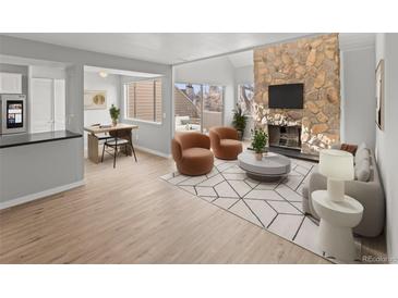 Bright living room featuring stone fireplace, neutral walls, and access to outdoor balcony at 13633 E Yale Ave # B, Aurora, CO 80014