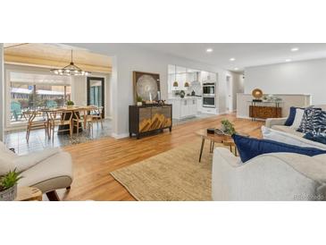 Open floor plan with hardwood floors, modern decor, seamlessly connecting the living, dining, and kitchen areas at 2784 E Maplewood Ave, Centennial, CO 80121