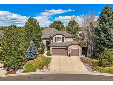 Beautiful two-story home with a three-car garage and manicured front lawn, surrounded by mature trees at 907 Greenridge Ln, Castle Pines, CO 80108