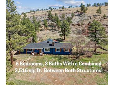 Charming blue ranch home with a covered front porch nestled on a hillside with mature trees at 5384 Olde Stage Rd, Boulder, CO 80302