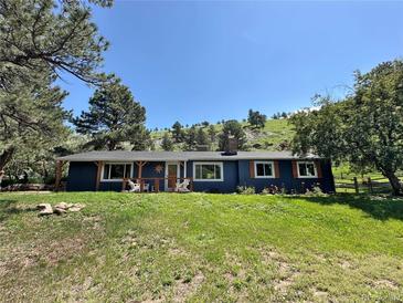 Charming blue ranch-style home featuring a covered porch and a well-manicured front yard in a scenic setting at 5384 Olde Stage Rd, Boulder, CO 80302