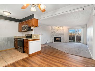 Bright living room features a stone fireplace, sliding glass doors, and an adjoining kitchen at 7040 W 20Th Ave # 206, Lakewood, CO 80214