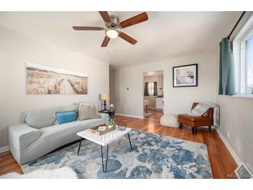 Bright living room features hardwood floors, comfy seating, and a view into the kitchen at 1665 Lima St, Aurora, CO 80010