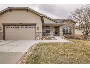 Charming home exterior with stone accents, a two-car garage, and a well-manicured lawn at 16399 Somerset Dr, Broomfield, CO 80023