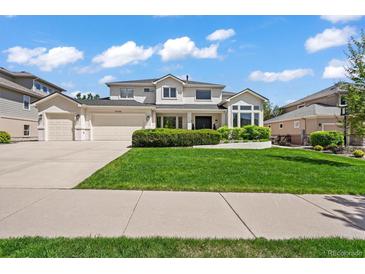 Charming two-story home featuring a three car garage, manicured lawn, and lush landscaping at 6566 S Telluride St, Aurora, CO 80016