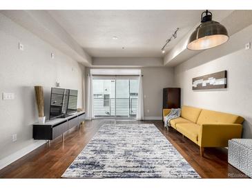 Bright living room featuring hardwood floors, modern lighting, and a sliding glass door to a balcony at 2650 Front View # 205, Denver, CO 80211