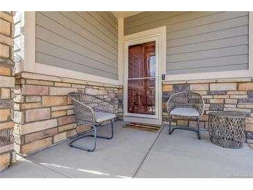 Inviting front porch with stone accents, gray siding, and stylish seating, perfect for relaxing outdoors at 18189 House Finch Ln, Parker, CO 80134